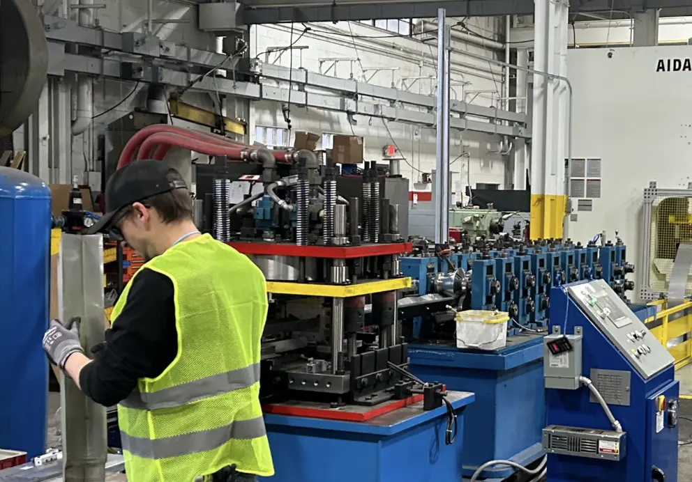 worker inspecting a roll form metal part on a factory floor